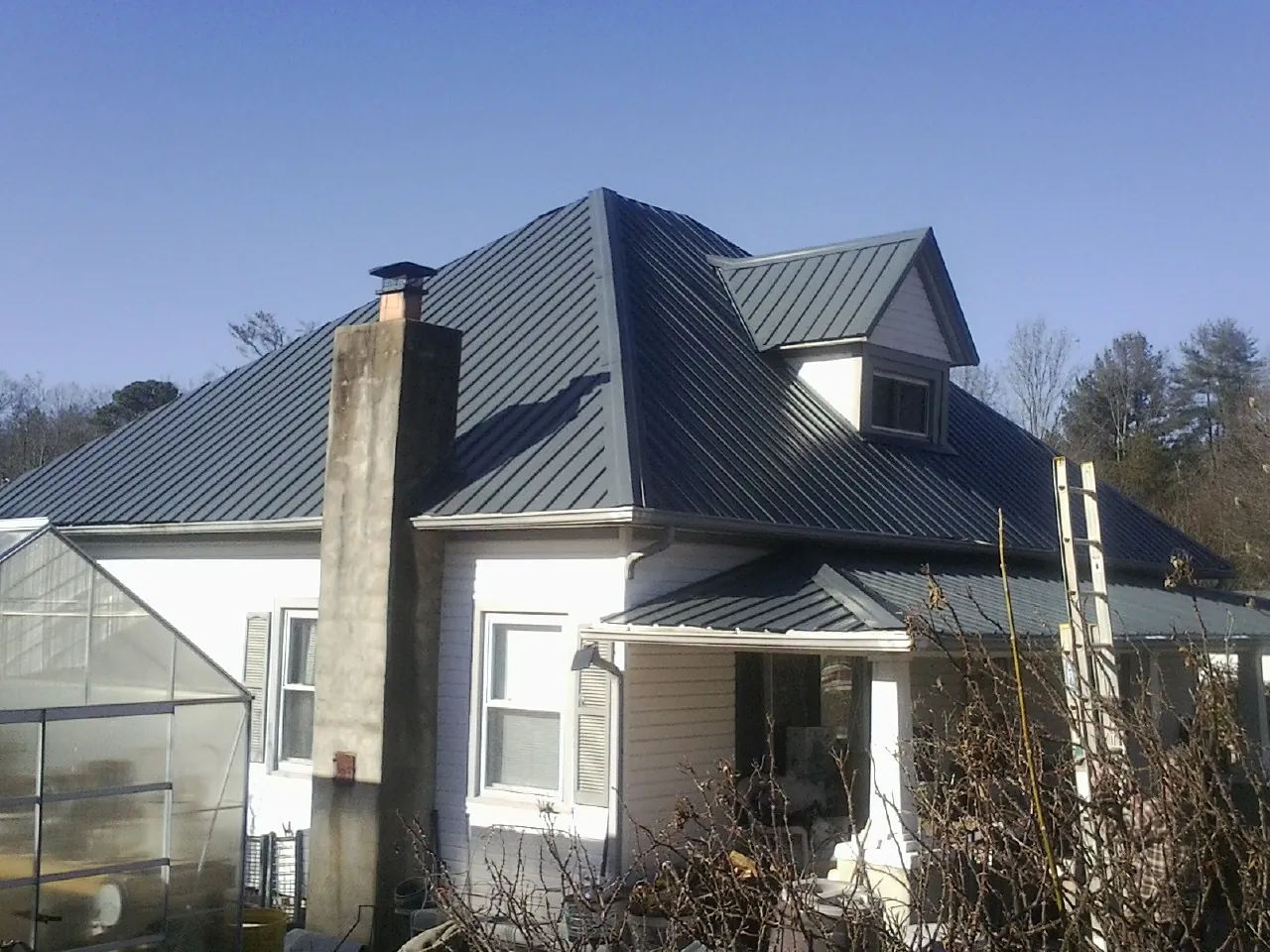 Dark blue standing seam metal roof on a white farmhouse with dormer — Slate & Tile Roof Repair by Roofing Brothers in Alabaster