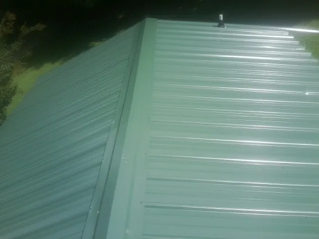 New green metal panels meeting at the ridge of a roof — Flat Roof Repair work by our crew in Alabaster