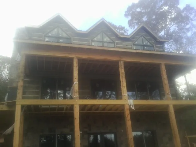Dormers and porch framing on a large log home under construction — Roof Coating work by our crew in Alabaster