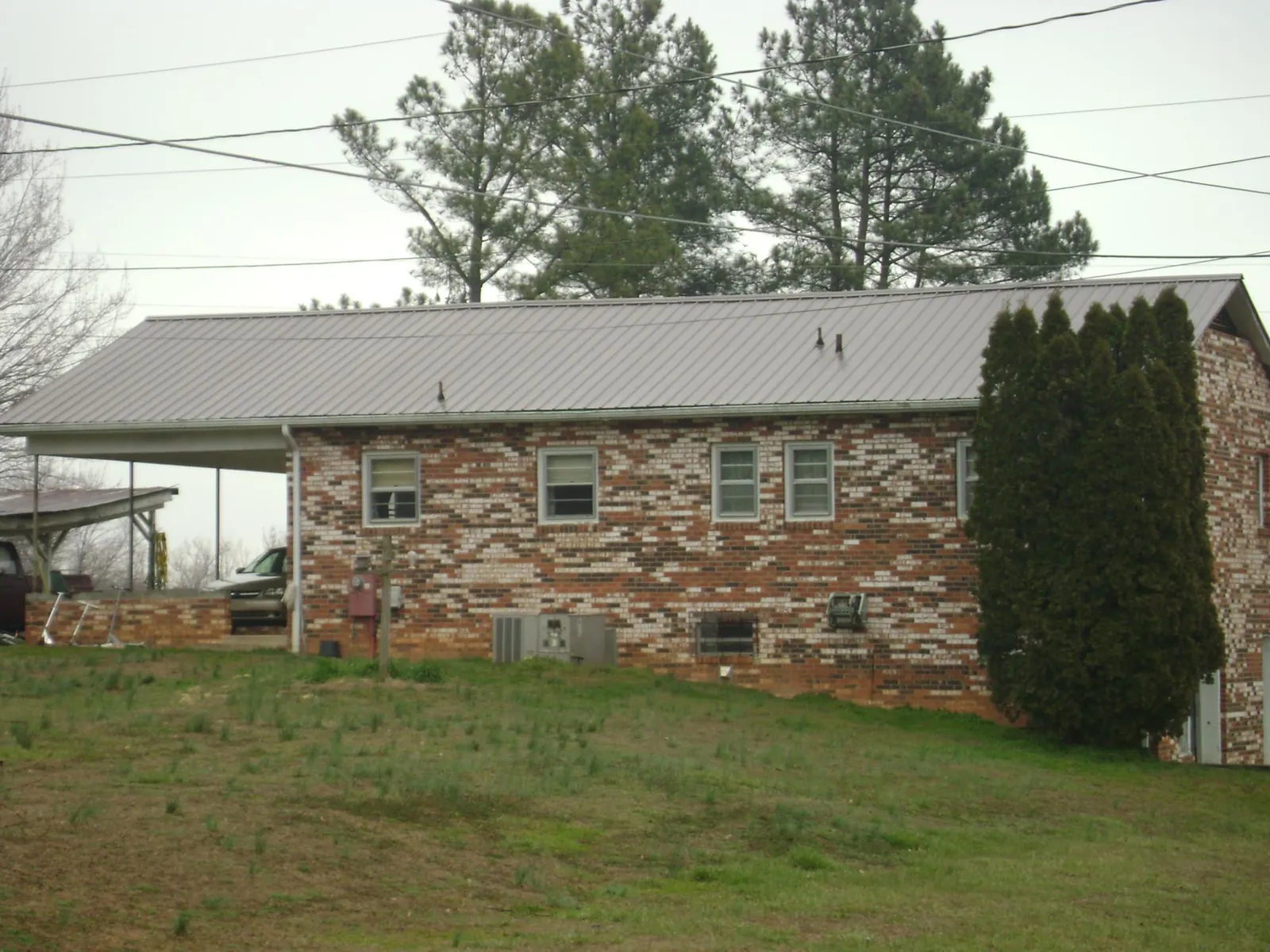 Gray metal roof on a brick split level home with a carport in Alabaster