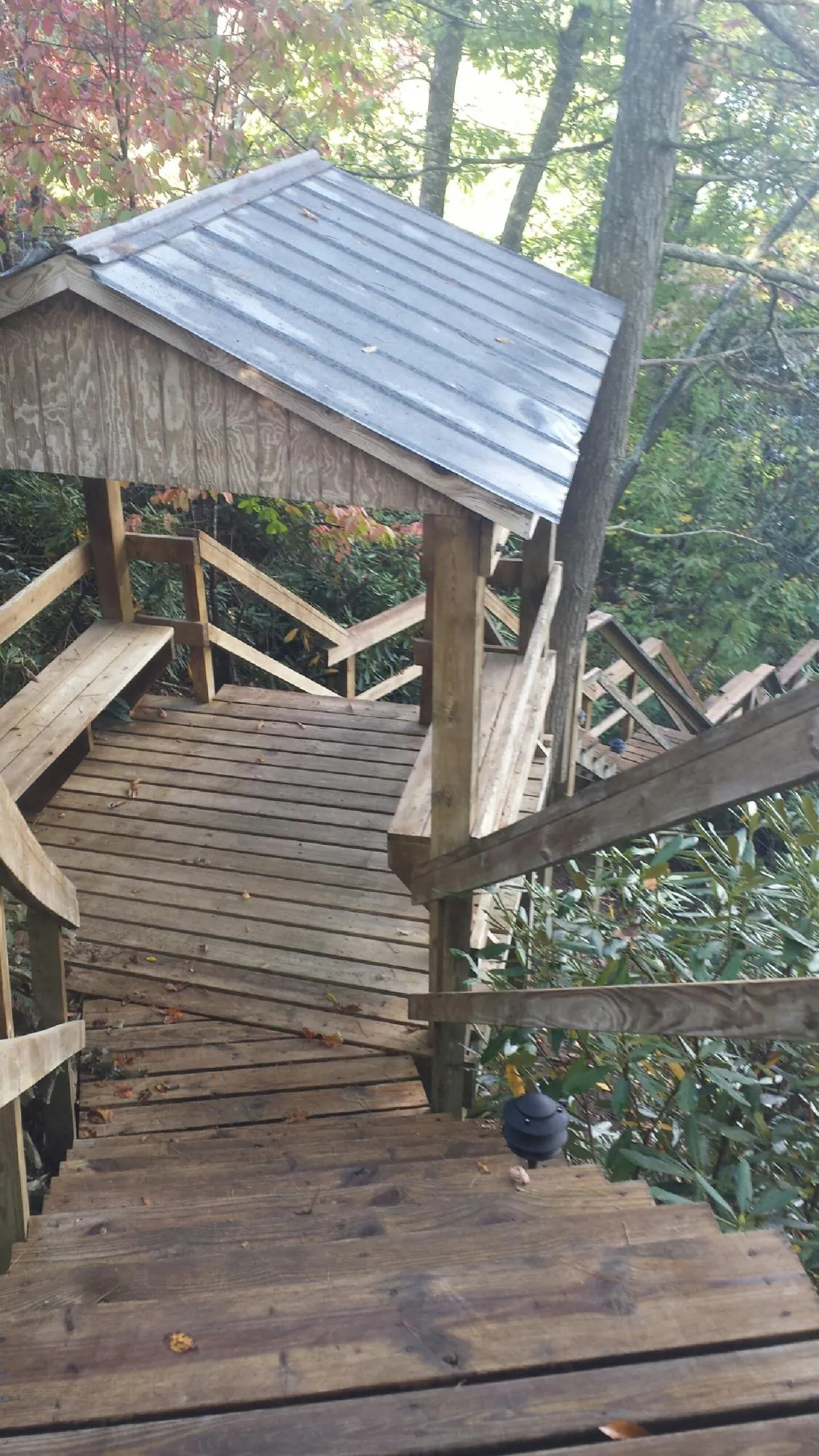 Metal roofed shelter over wooden steps on a wooded walkway — Skylight Repair & Installation work by our crew in Alabaster