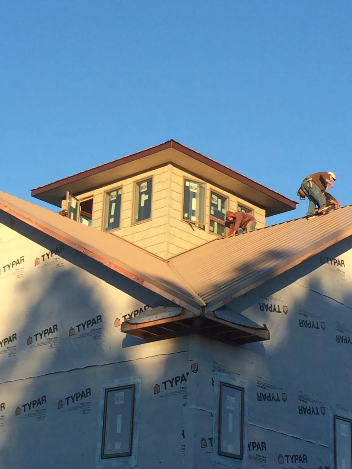 Roofers working around a rooftop cupola on a new metal roof at sunset — Roof Waterproofing in Alabaster by Roofing Brothers